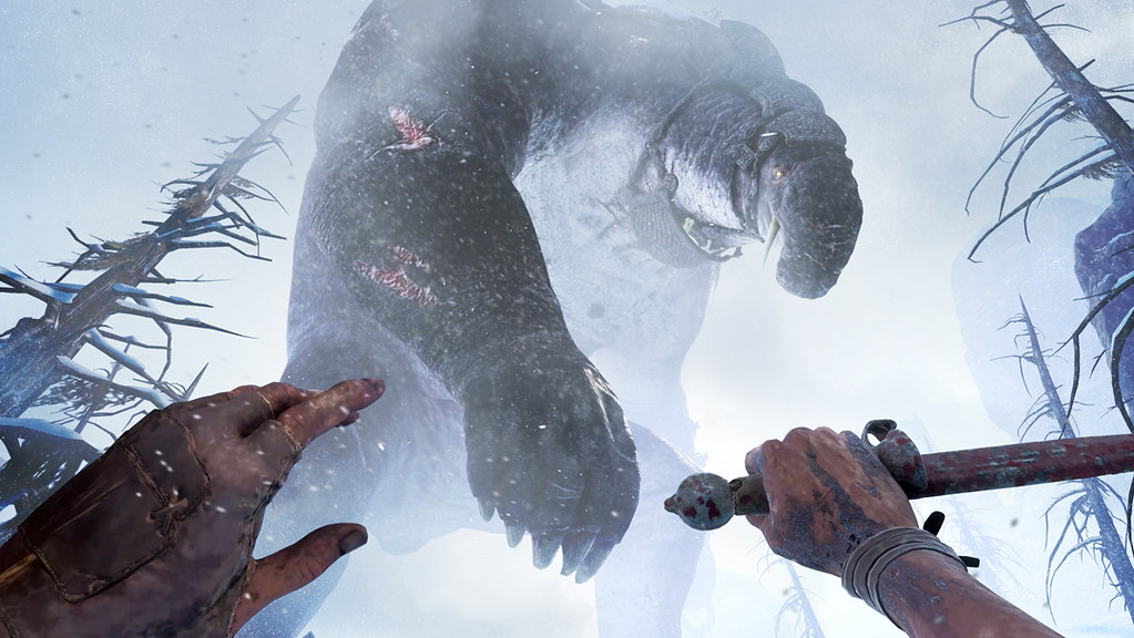 A POV shot. In the middle of a blizzard, the player gazes above them as a behemoth strides by, the monster’s head bent down to observe the tiny figure at its feet.