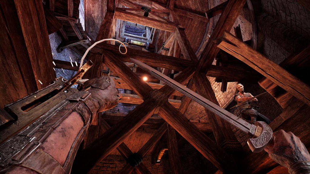 A POV shot. Inside a wooden tower, the player aims and fires their grappling hook up towards a grappling point. In their right hand, they have a sword raised, ready to attempt a deflection of an arrow fired by a nearby enemy who cocks their bow while standing on the platform directly above.